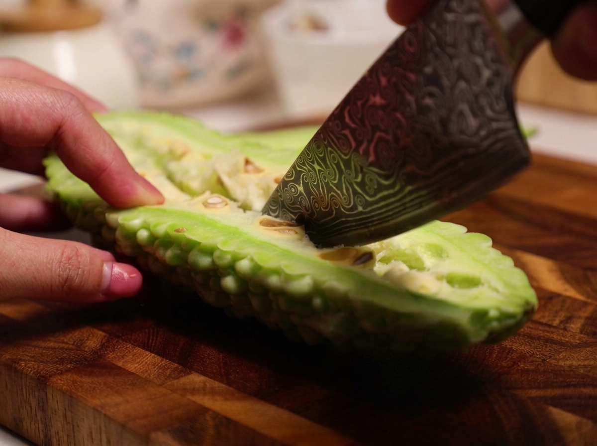 Un coltello usato per raschiare il midollo bianco e i semi dallinterno di un melone amaro crudo tagliato a metà.