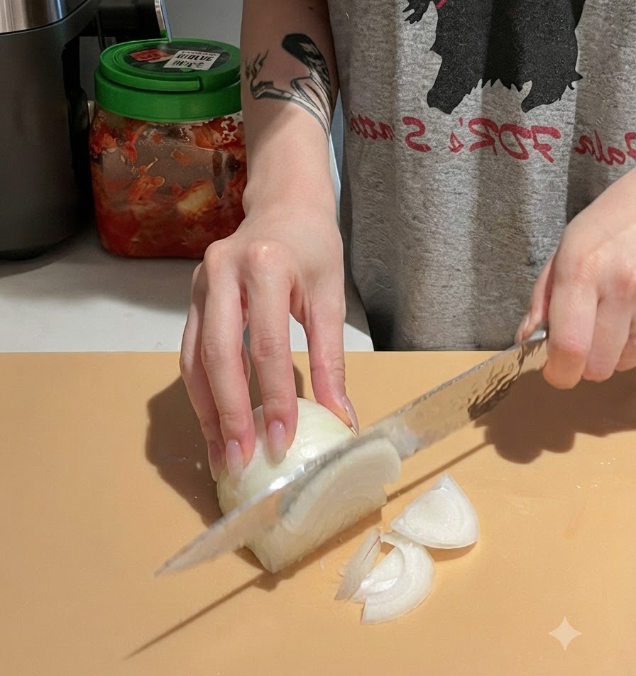 Mani che affettano con cura una cipolla bianca su un tagliere usando un coltello da cucina.