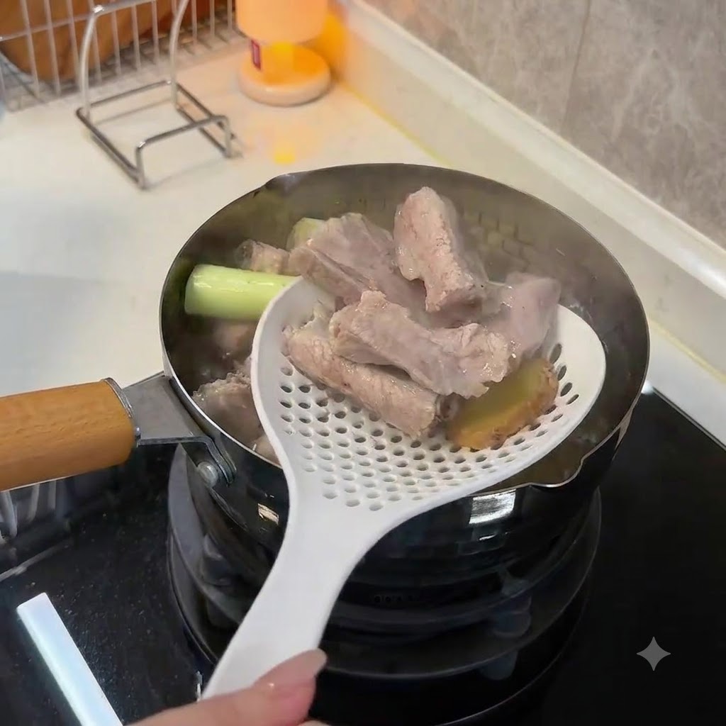 Uso di un cucchiaio forato bianco per sollevare costine di maiale sbollentate e opache e fette di zenzero fuori dallacqua bollente.