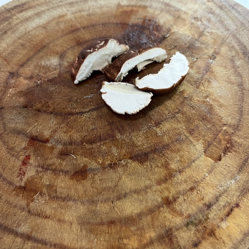 Funghi shiitake freschi tagliati sottilmente su un tagliere di legno.