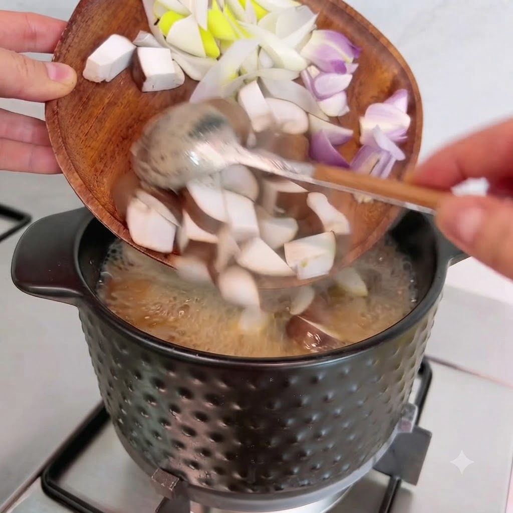 Funghi shiitake, cipolle e cipollotti a cubetti vengono versati da un piatto di legno nella pentola.
