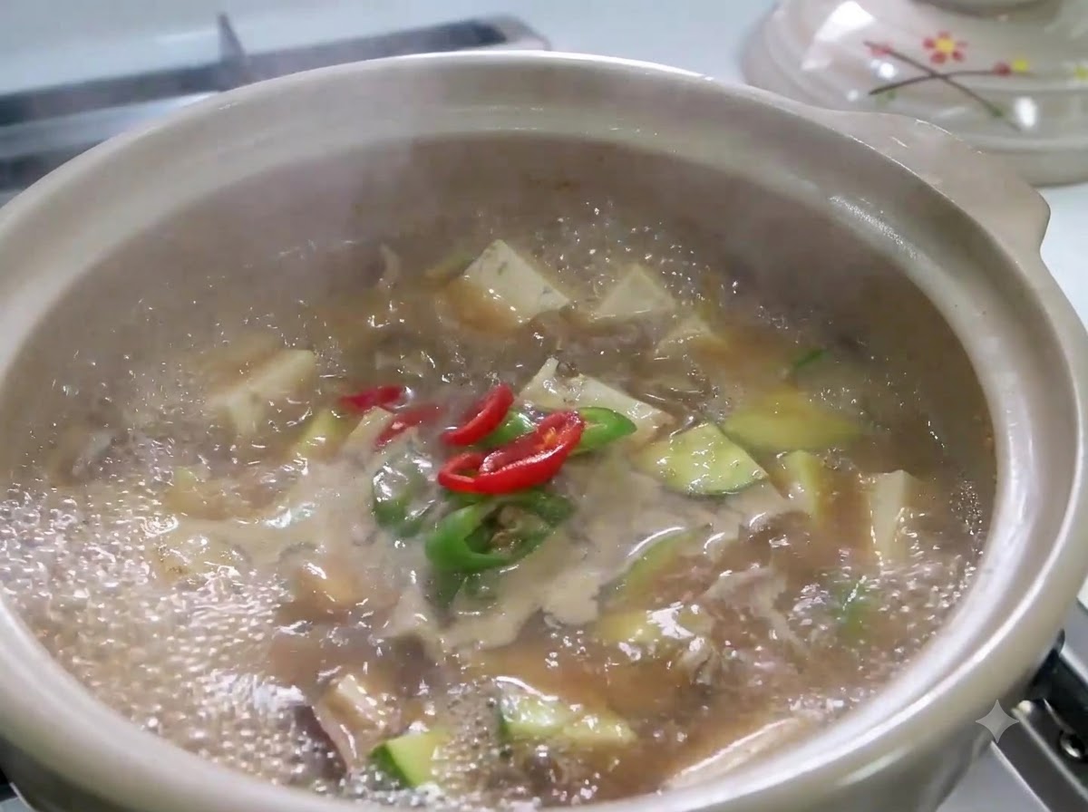 Peperoncini rossi e verdi affettati e cipollotti che sobbollono in una pentola bollente di Doenjang Jjigae.