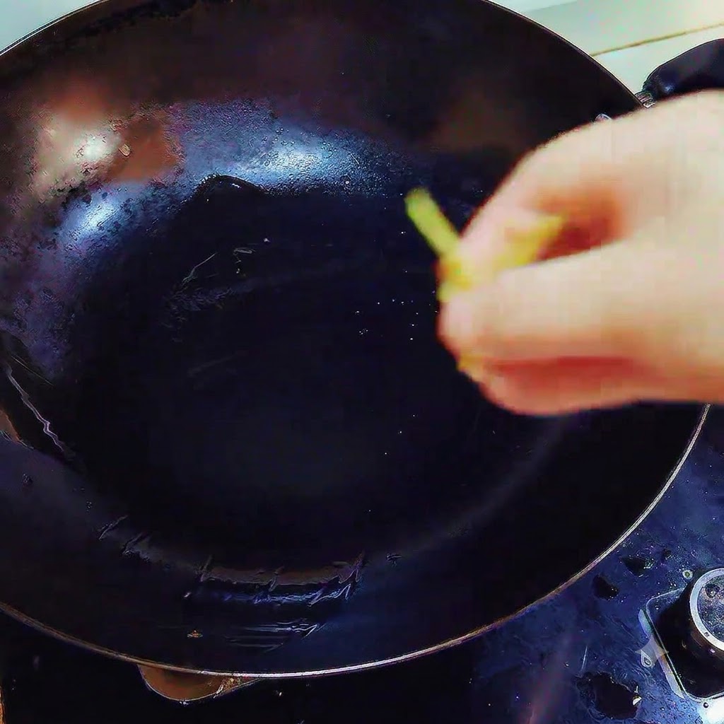 Pezzi di zenzero e aglio fatti cadere in un wok contenente strutto sciolto sul fuoco.