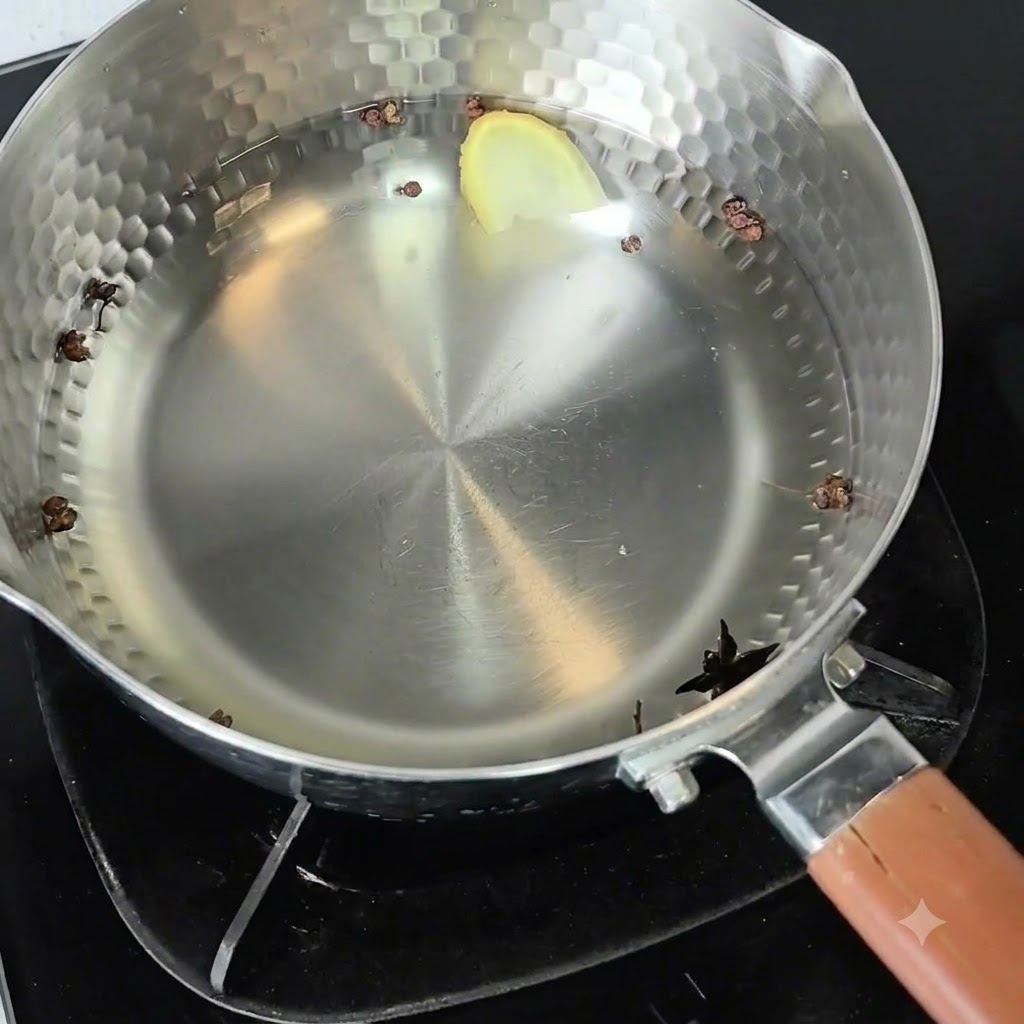 Una pentola di metallo piena dacqua fredda, pepe di Sichuan, anice stellato e una fetta di zenzero sul fornello.