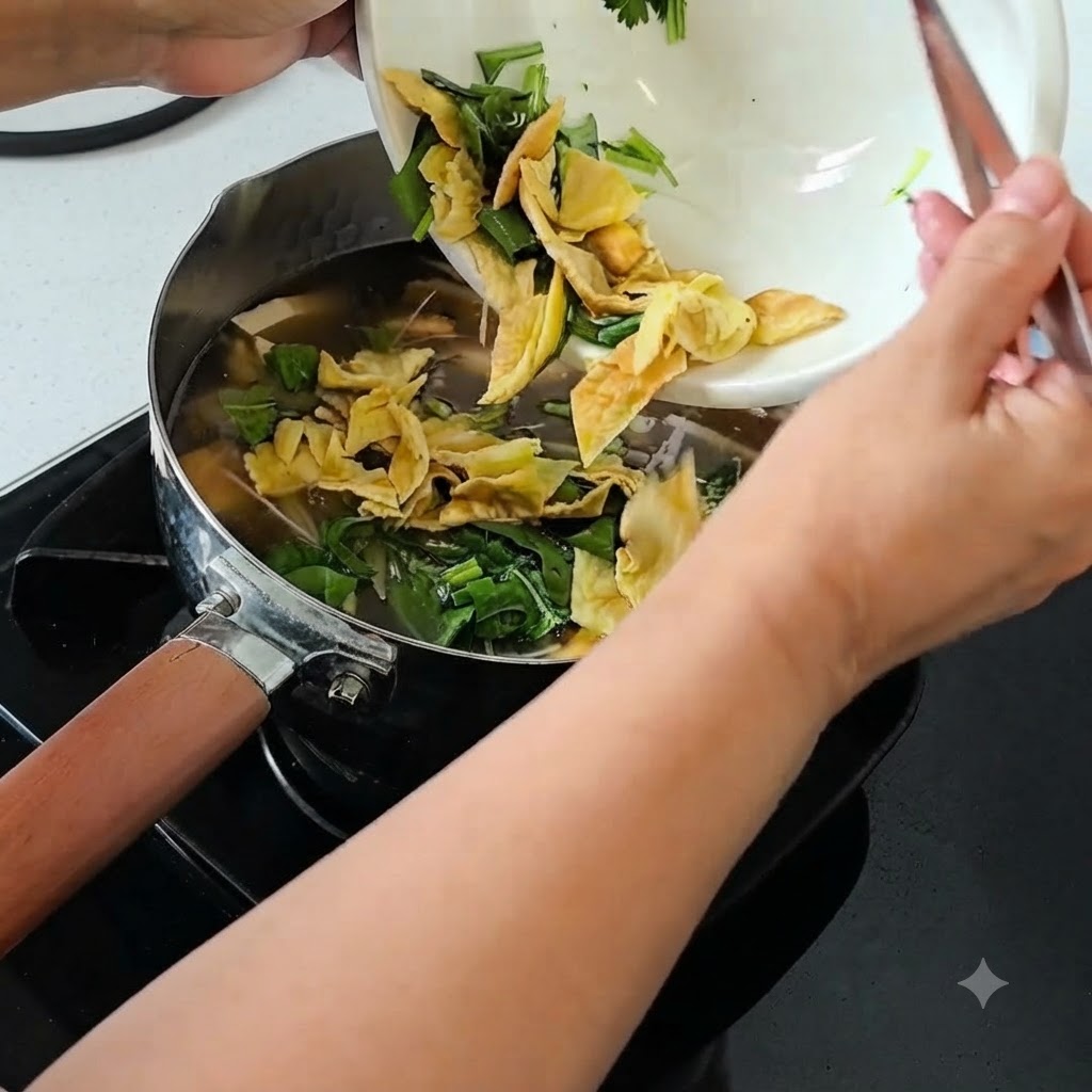 Cipollotti a julienne, coriandolo e uovo centenario a pezzi versati da una ciotola in una zuppa a fuoco lento.