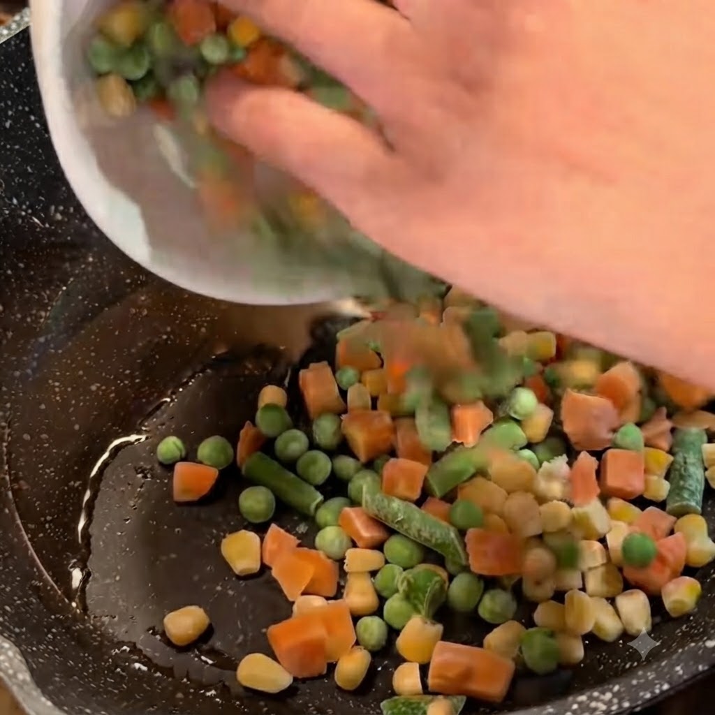 Verdure miste surgelate versate da una ciotola bianca in una padella con olio e cipollotti.