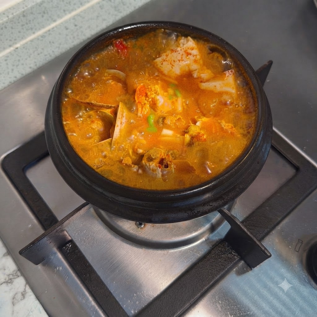 Zuppa coreana piccante di tofu morbido finita e guarnita con cipollotti tritati in una pentola di pietra calda.