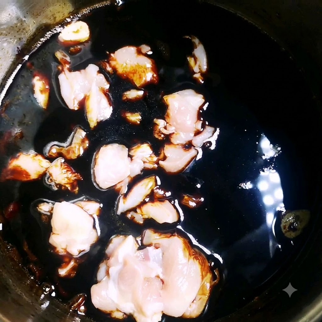 Pezzi di pollo crudo che sobbollono in una salsa scura e saporita allinterno di una pentola.