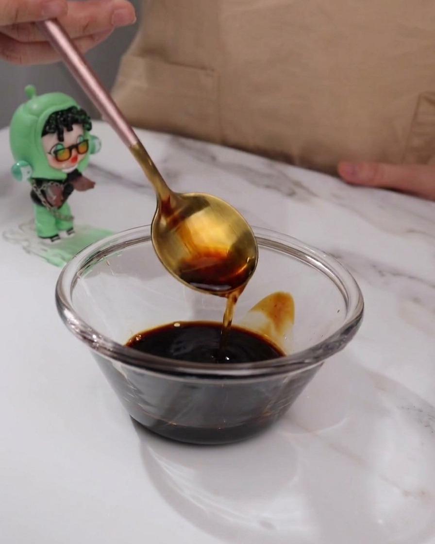 Ingredienti della salsa teriyaki mescolati in una piccola ciotola di vetro con un cucchiaio.