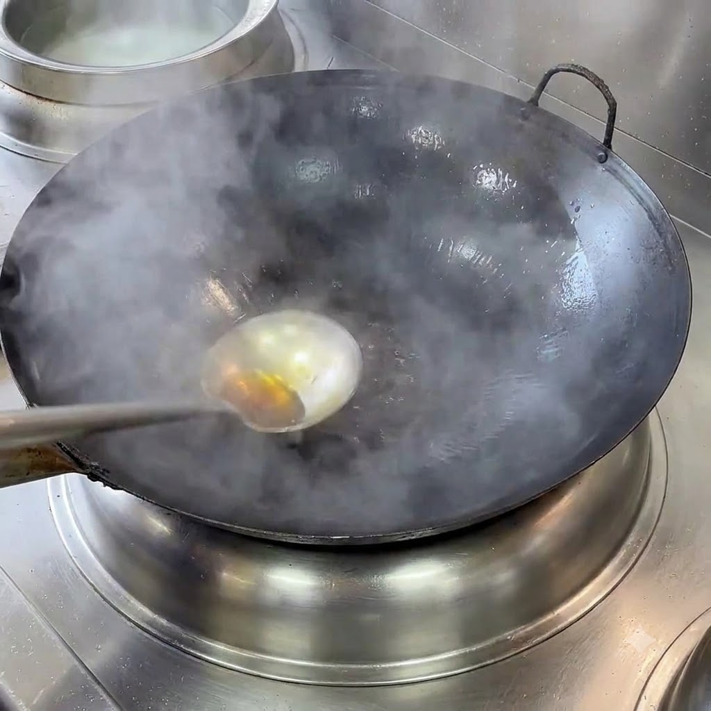 Un wok in ghisa fumante con un mestolo e olio caldo scaldato su un fornello.