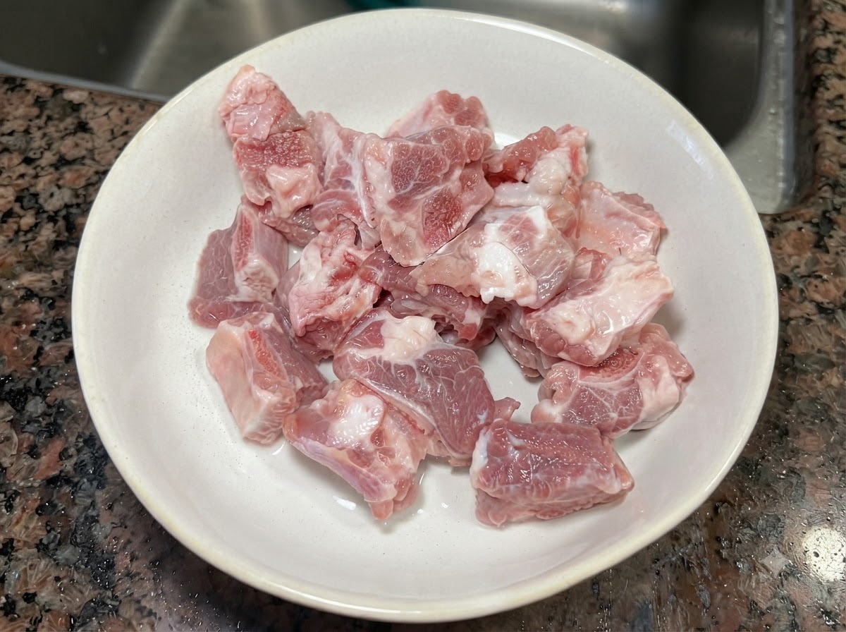 Pezzi di costine di maiale crude e fresche allinterno di una ciotola di ceramica bianca.