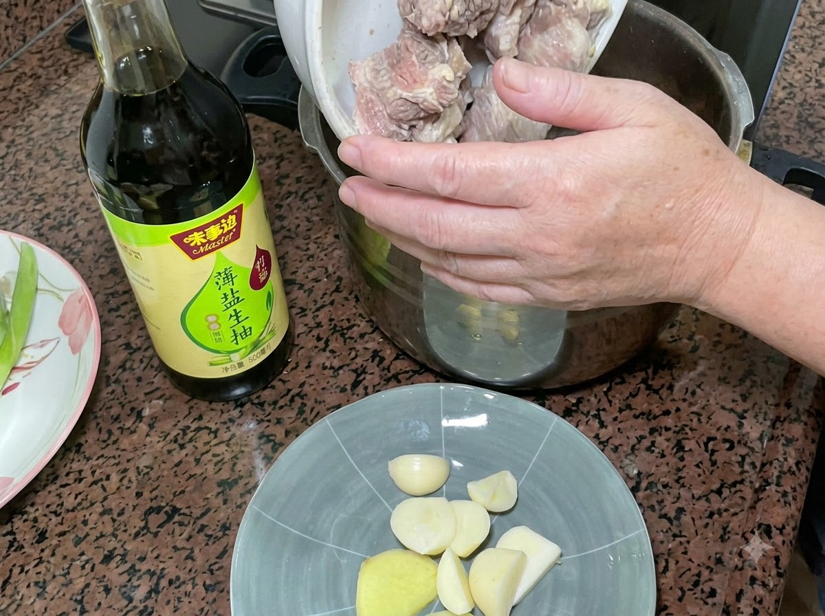 Costine di maiale sbollentate versate in una pentola a pressione accanto a una bottiglia di salsa di soia chiara e un piatto di aglio e zenzero.