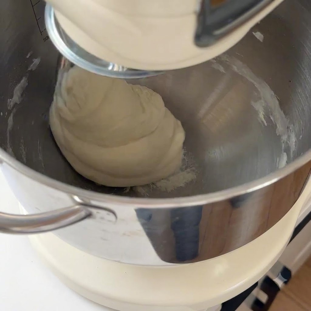 Impasto per pizza liscio in lavorazione allinterno della ciotola di una planetaria.