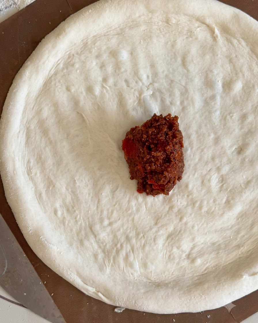 Un cucchiaio di ragù di carne adagiato al centro del disco di pasta.