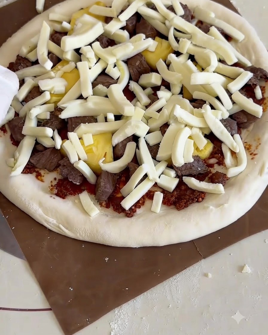 Una pizza cruda e condita su una pala di legno mentre viene infilata in un fornetto per pizza con pietra refrattaria.