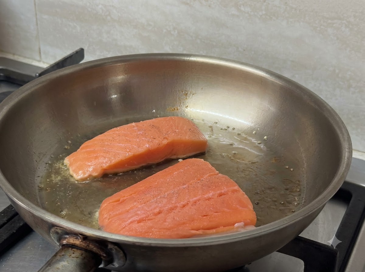Due filetti di salmone che sfrigolano e dorano in una padella calda.