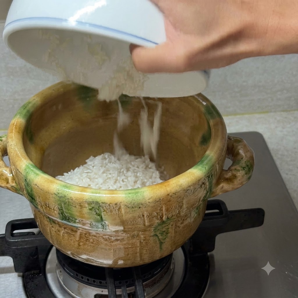 Brodo di vongole limpido versato da una ciotola bianca in una casseruola di ceramica contenente riso bianco su un fuoco a gas.