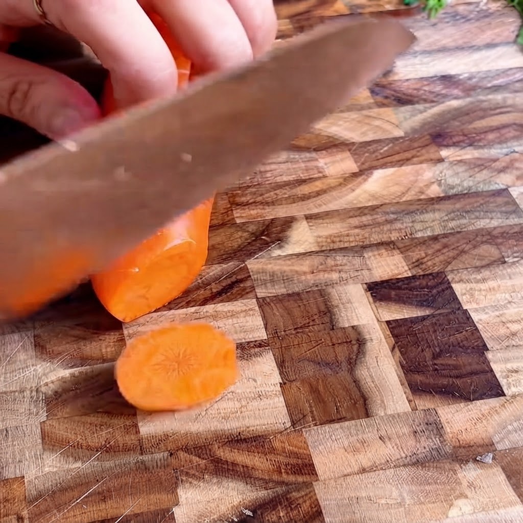 Rondelle di carota disposte ordinatamente su un tagliere di legno.