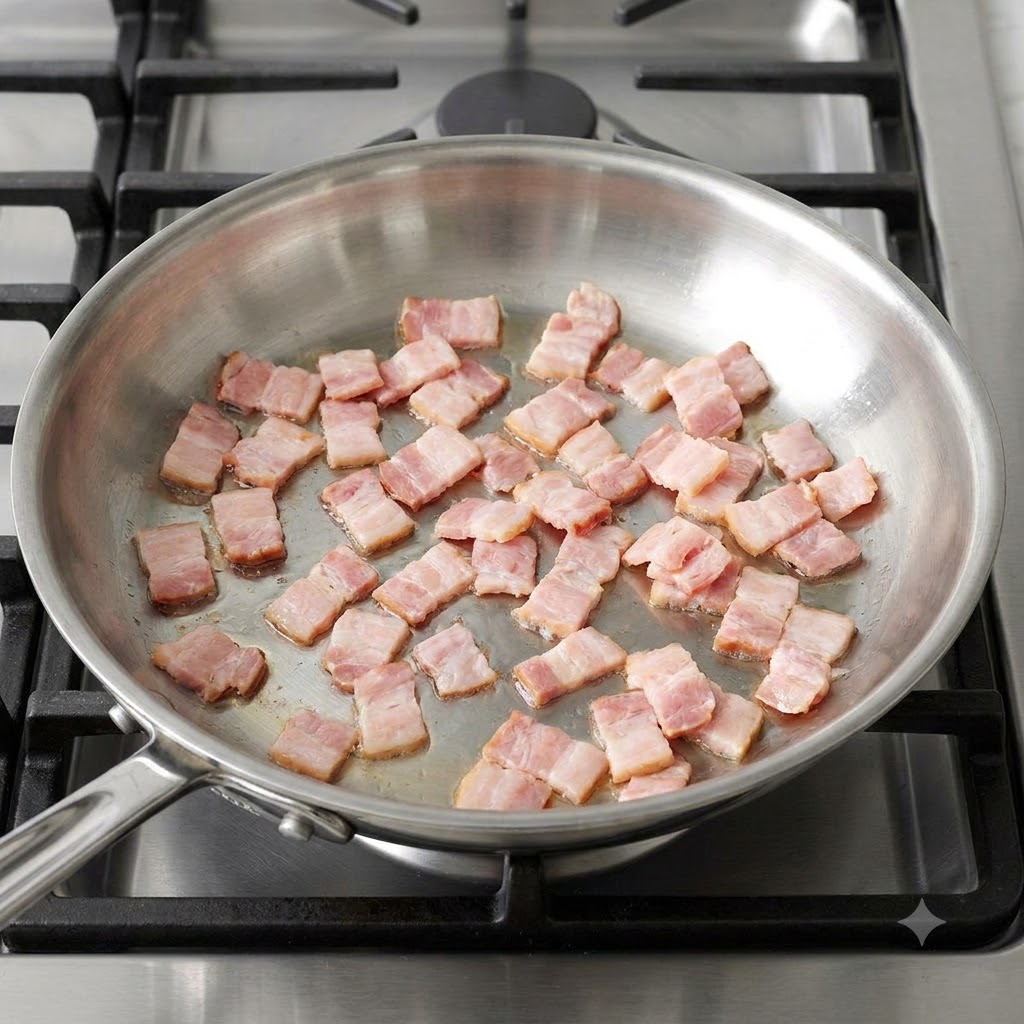 Cubetti di pancetta che sfrigolano e si rosolano in una padella di acciaio.