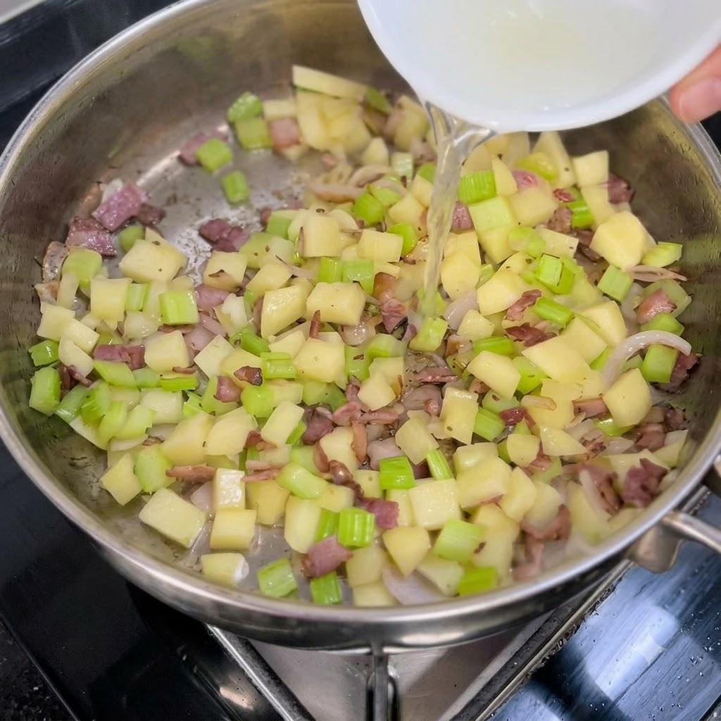 Brodo chiaro di vongole versato da una ciotola bianca in una padella di verdure saltate e pancetta.