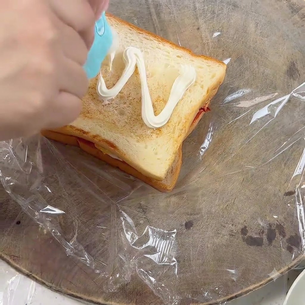 Spremitura della maionese a zig-zag su una fetta di pane tostato.