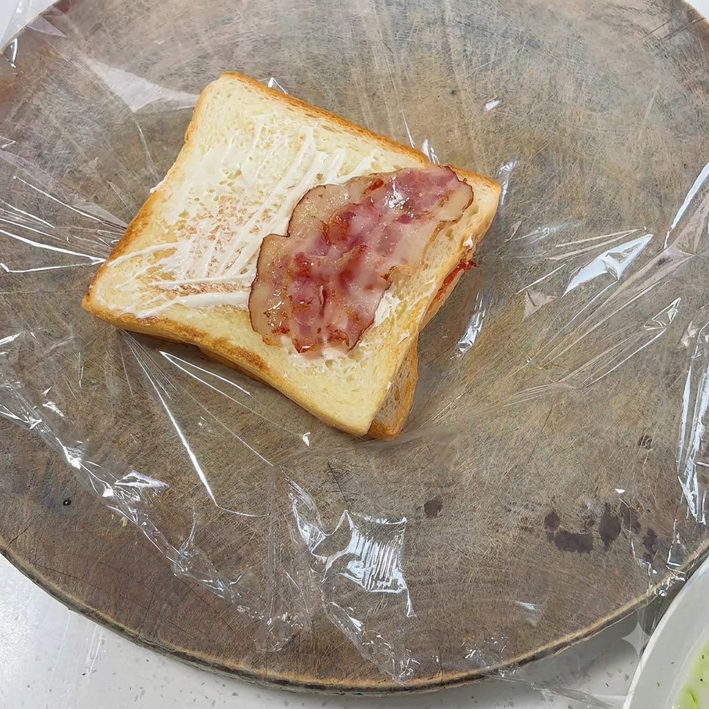 Pezzi di pancetta cotta disposti sopra il pane tostato.
