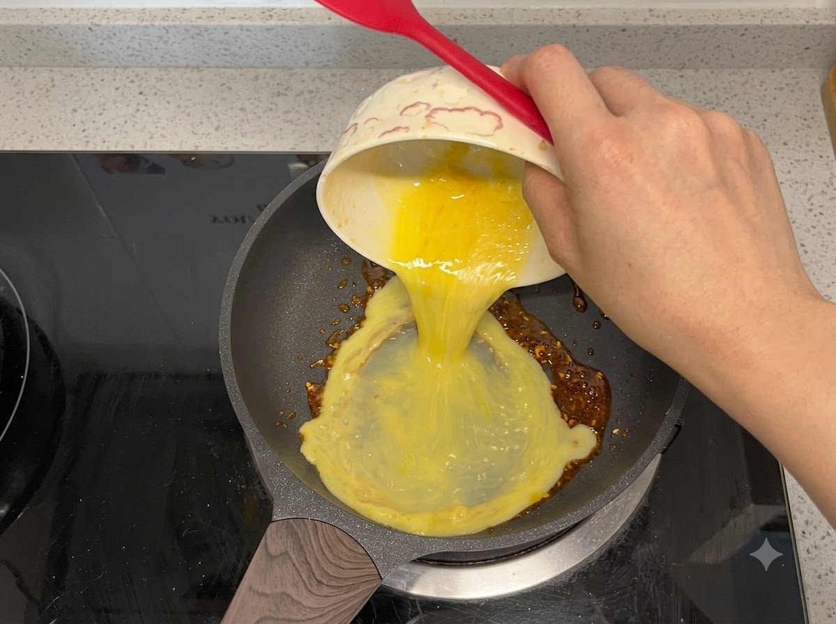 Uova sbattute versate in una padella con olio al peperoncino.