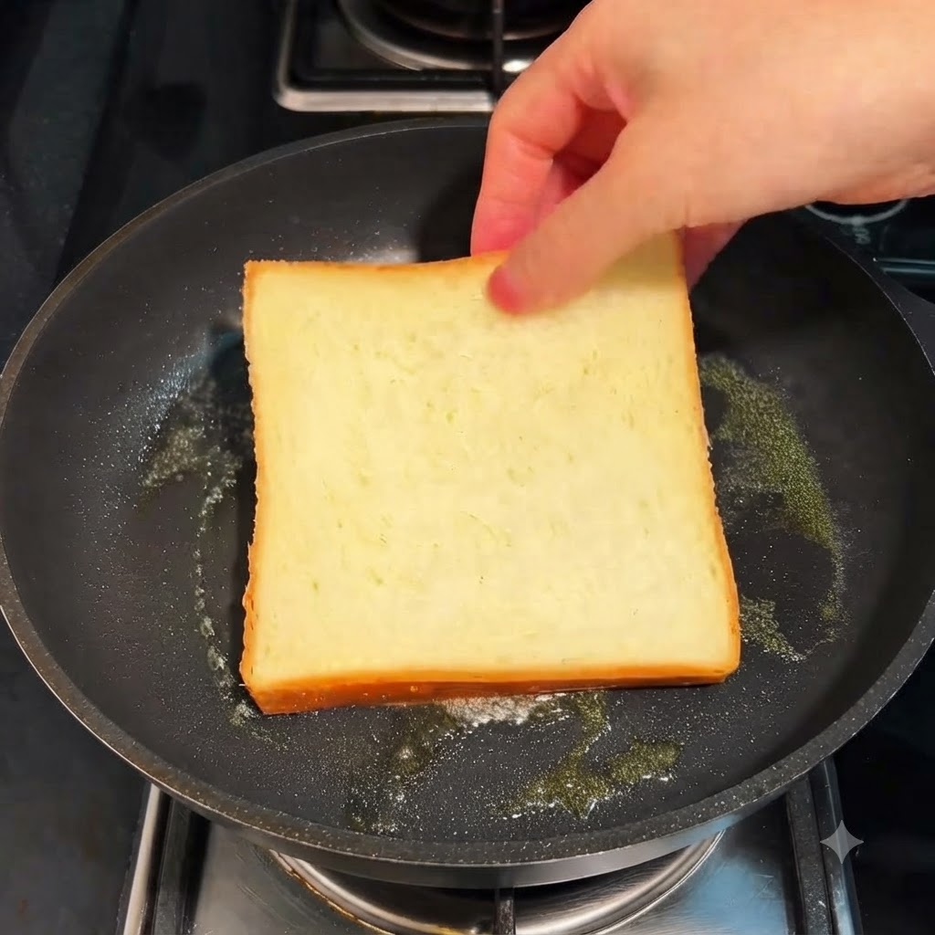 Una fetta di pane bianco che si tosta in padella con il burro a fiamma bassa.
