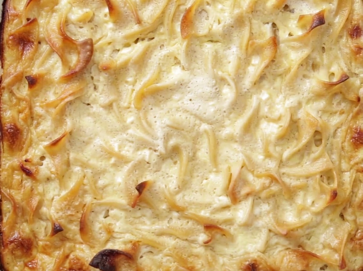 Un coltello che taglia un kugel cotto e refrigerato in una teglia di vetro.