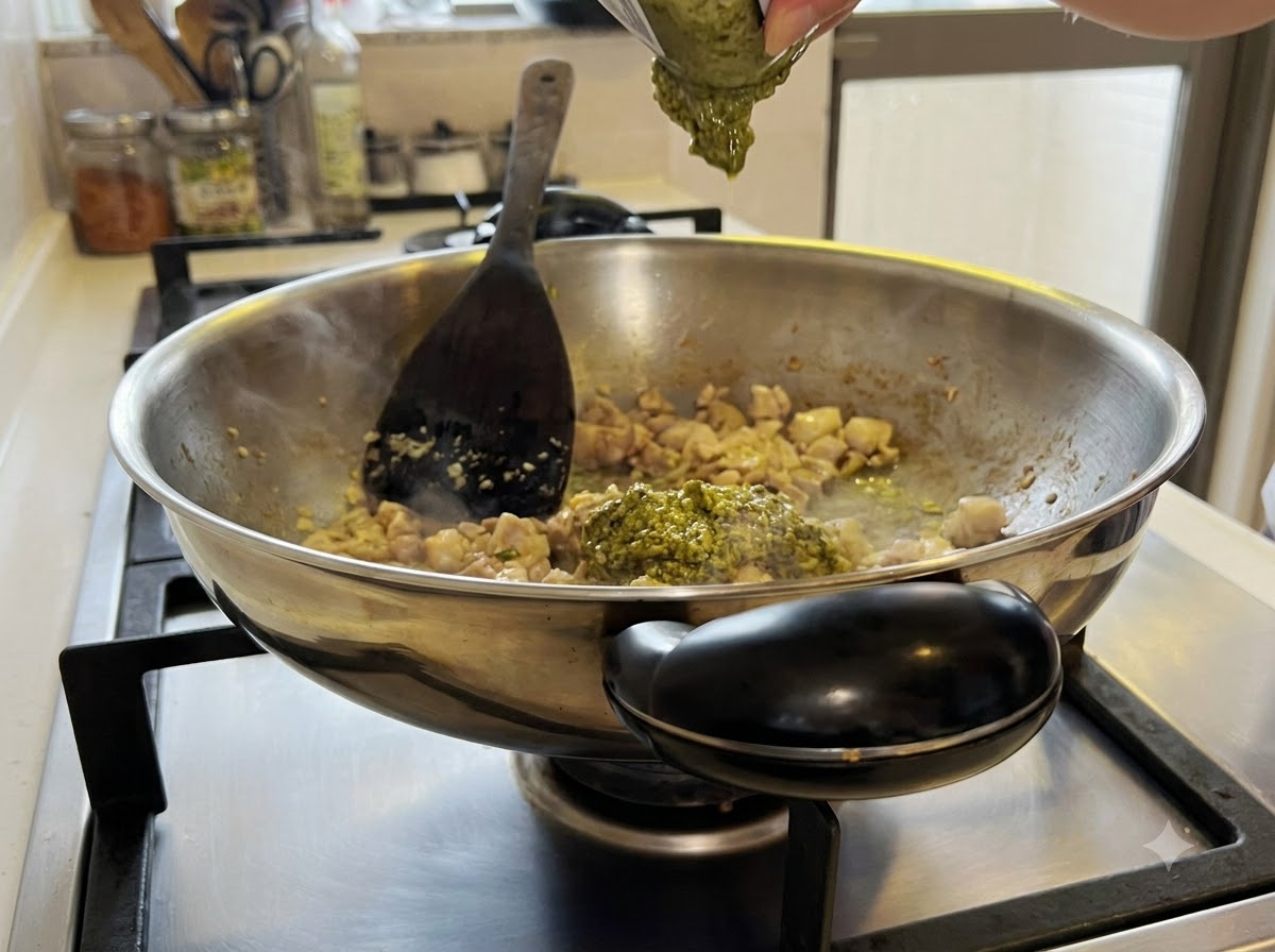 Salsa di pesto verde mescolata nel composto di pollo e aglio allinterno del wok.