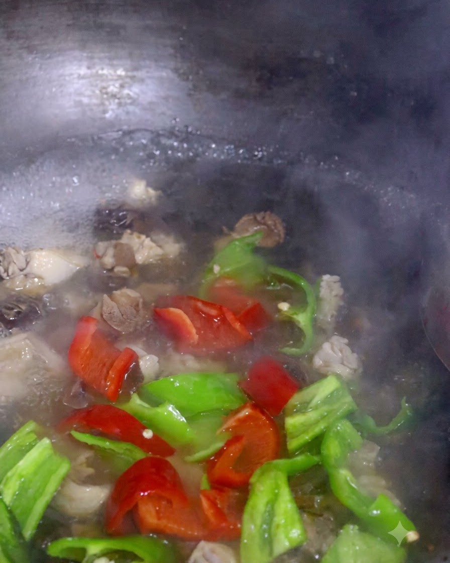 Fette di peperone rosso e verde e bok choy che bollono insieme ai funghi in una pentola.