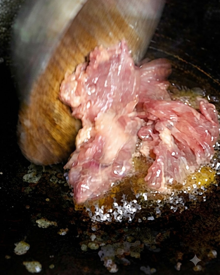Carne tritata aggiunta allolio caldo in una padella usando una spatola di legno.