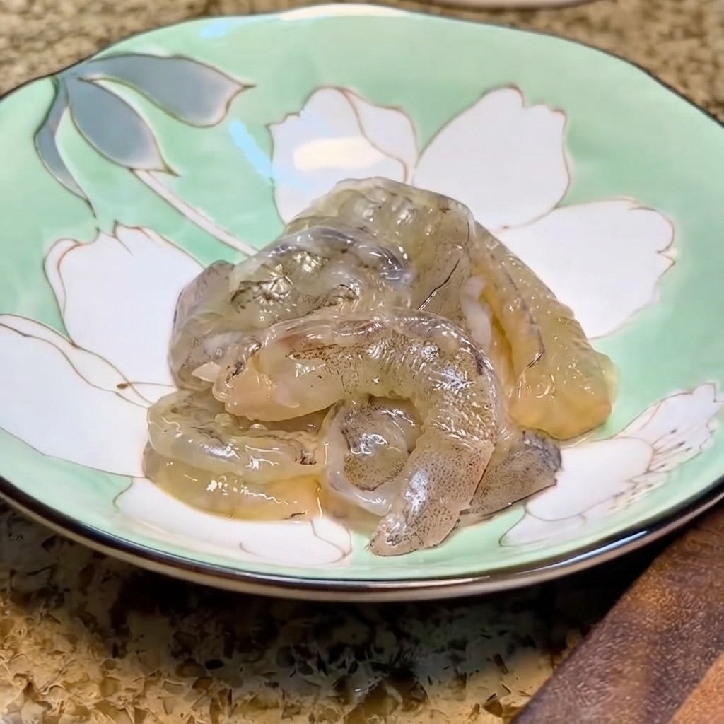 Gamberi freschi allinterno di una ciotola di ceramica floreale verde chiaro pronti per la marinatura.