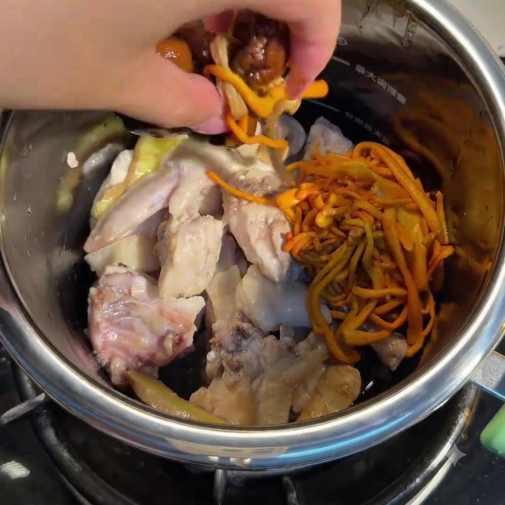 Mano che aggiunge funghi ammollati e fiori di cordyceps nella pentola con il pollo.