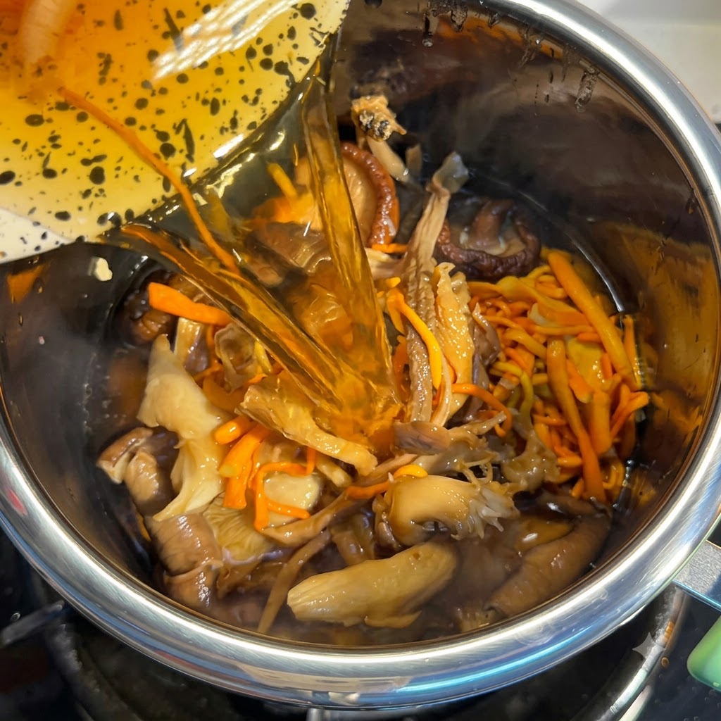 Acqua di ammollo dei funghi versata nella pentola piena di ingredienti.