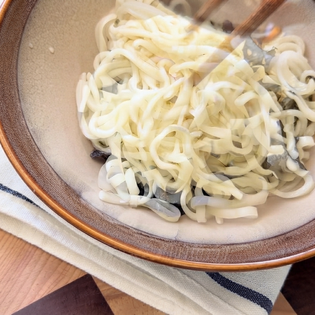 Zuppa di funghi calda versata dallalto sui noodle allinterno della ciotola da portata.