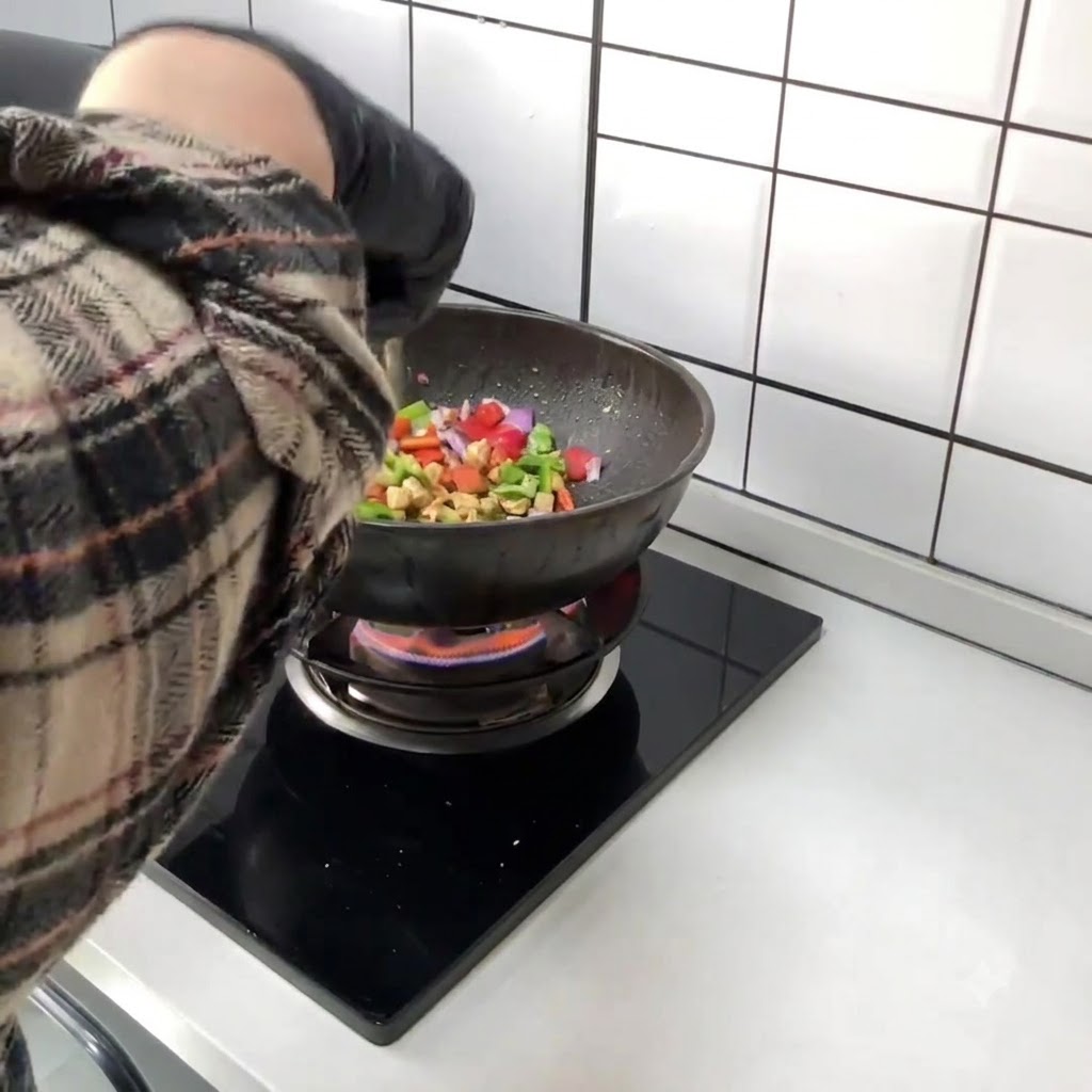 Peperoni rossi e verdi tagliati a tocchetti aggiunti direttamente nel wok insieme al pollo saltato.
