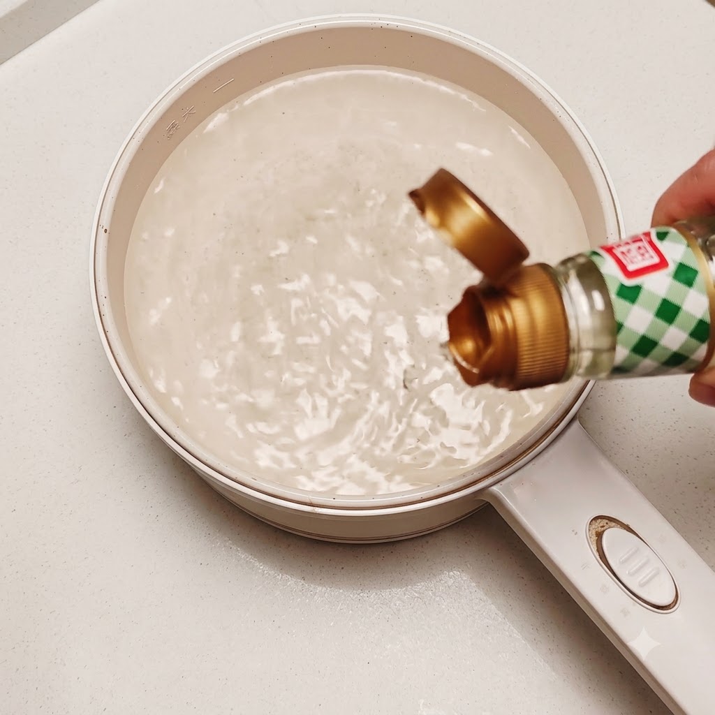 Un uovo crudo sgusciato fatto cadere in una pentola di acqua calda in movimento con un goccio di aceto di riso.