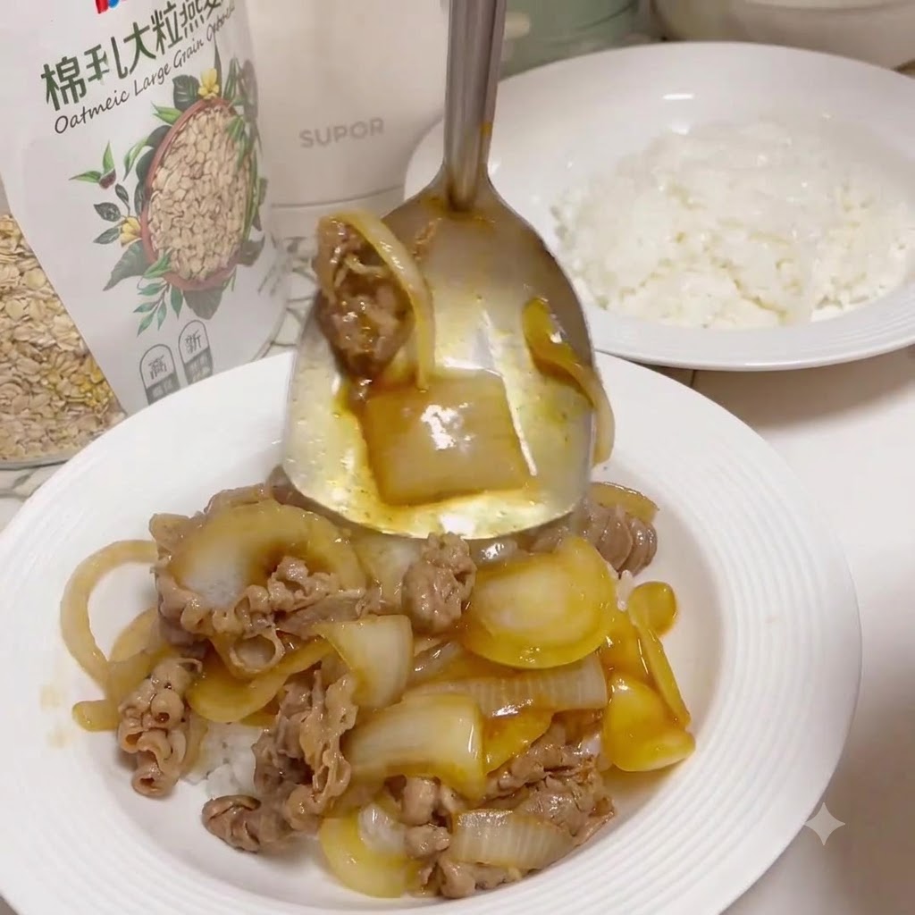 Un cucchiaio da portata in metallo che raccoglie manzo cotto e cipolle glassate da una padella per versarli su un piatto bianco pieno di riso bianco cotto.