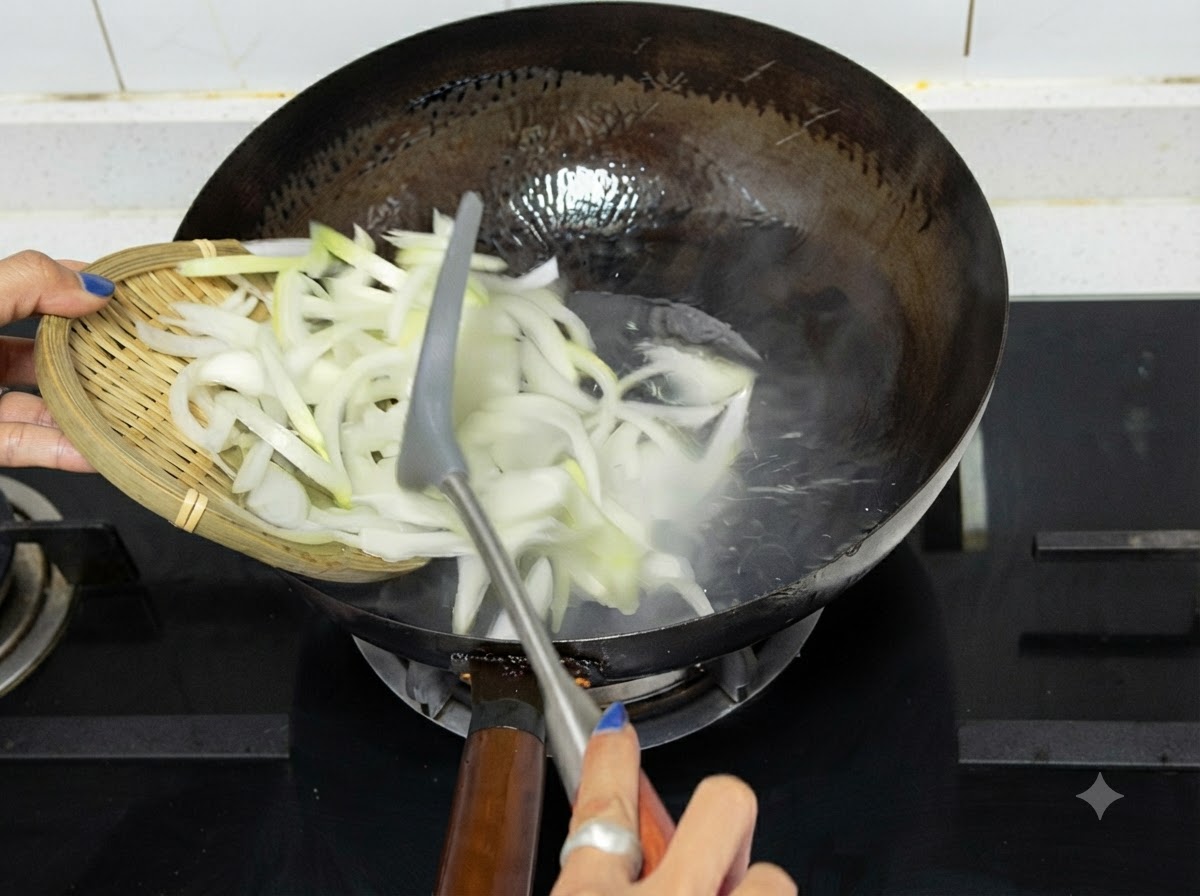Cipolle affettate versate da un vassoio di legno in un wok caldo su un piano cottura.