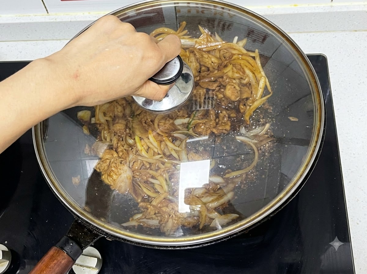 Un coperchio di vetro posizionato sopra un wok contenente manzo e cipolle in cottura a fuoco lento.