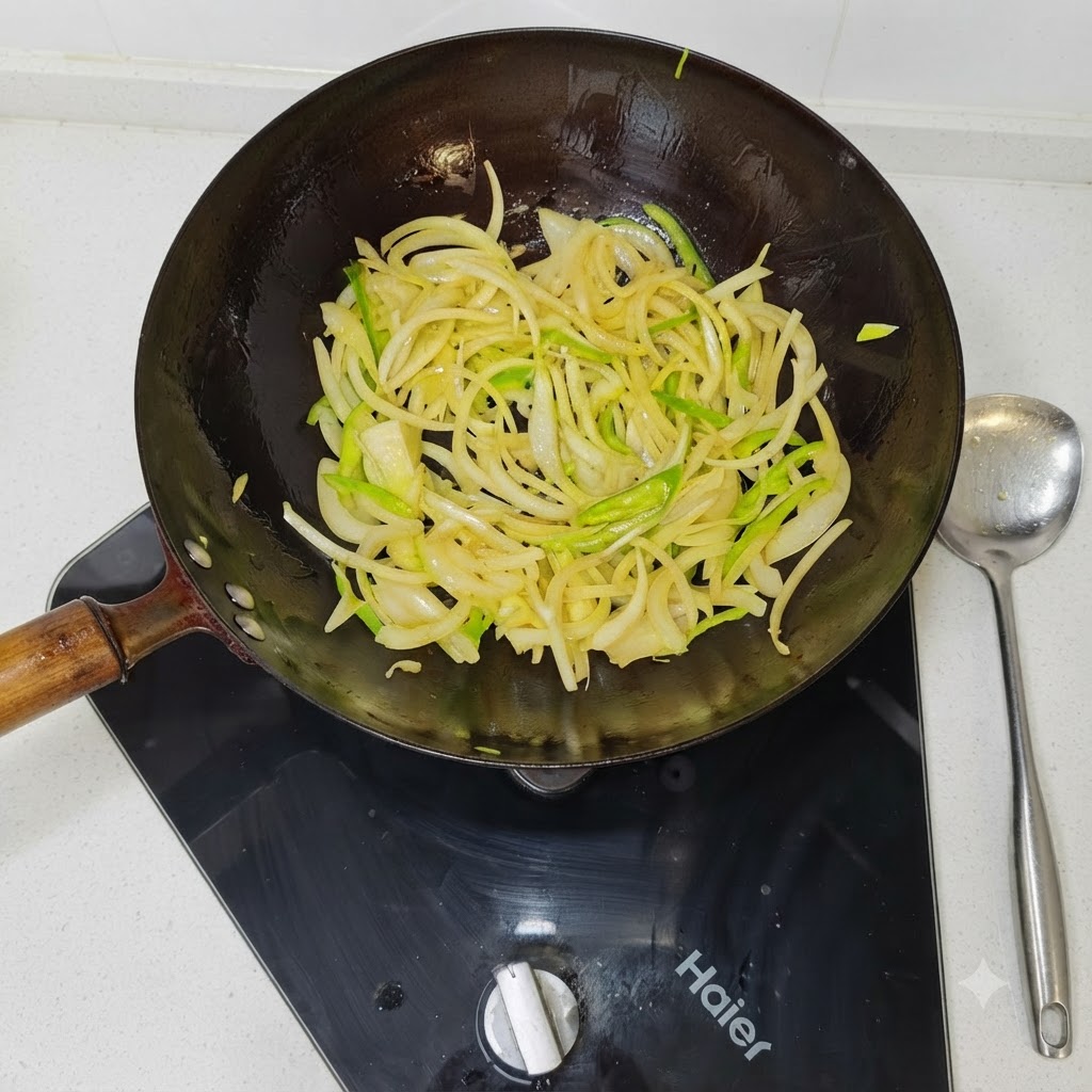 Fette di cipolle e peperoni verdi saltate in un wok nero ben caldo.