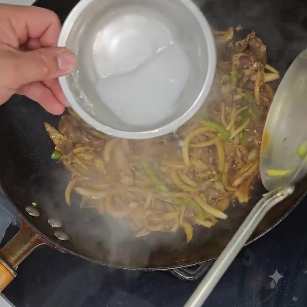 Slurry di fecola di patate versato da una ciotolina in un wok pieno di manzo e verdure in cottura.