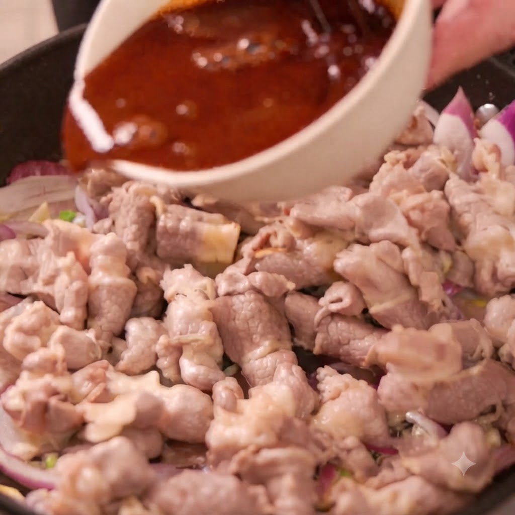 Una ciotola di salsa scura versata in una padella piena di involtini di manzo e cipolle rosse affettate.
