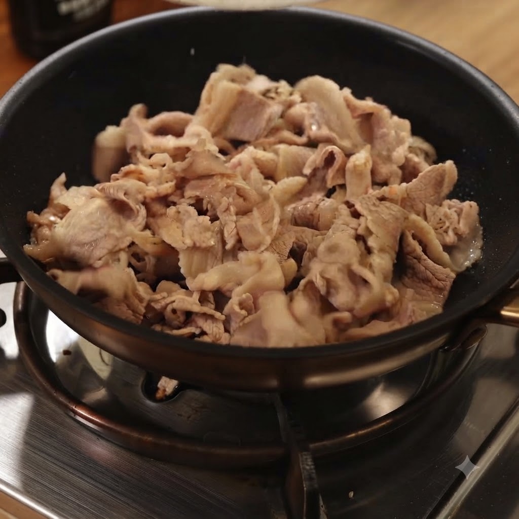 Fettine di manzo sbollentate saltate in una padella nera su un fornello a gas.