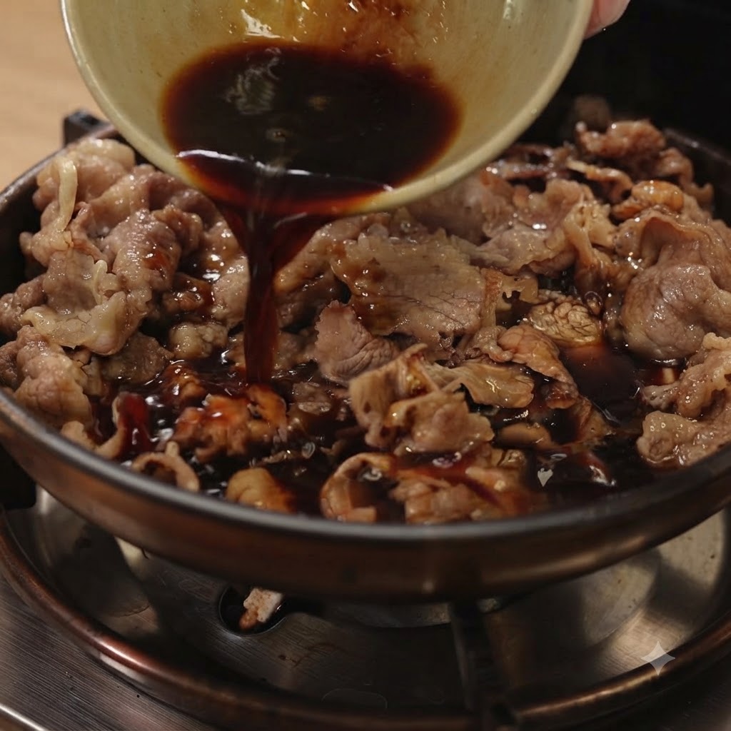 Salsa teriyaki scura versata da una piccola ciotola in una padella piena di manzo a fette e cipolle rosse.