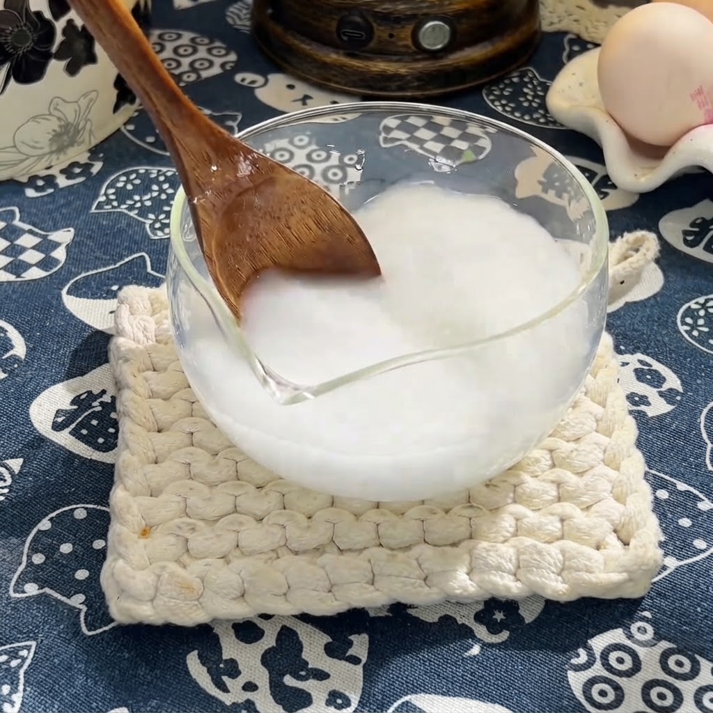 Un cucchiaio di legno che mescola salsa di soia, salsa di ostriche e miele nella miscela di fecola di mais.