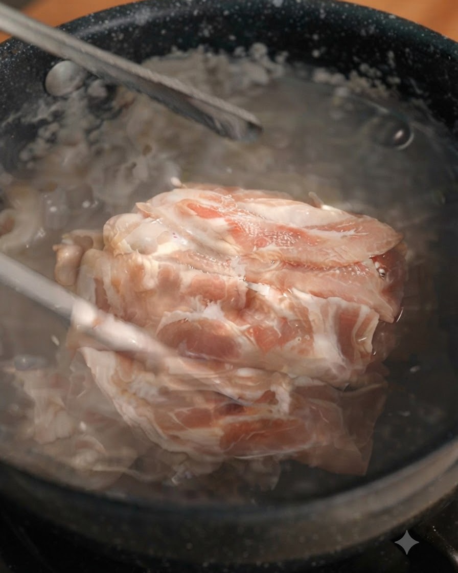 Fette di manzo sbollentate sollevate da una pentola bollente con le pinze.