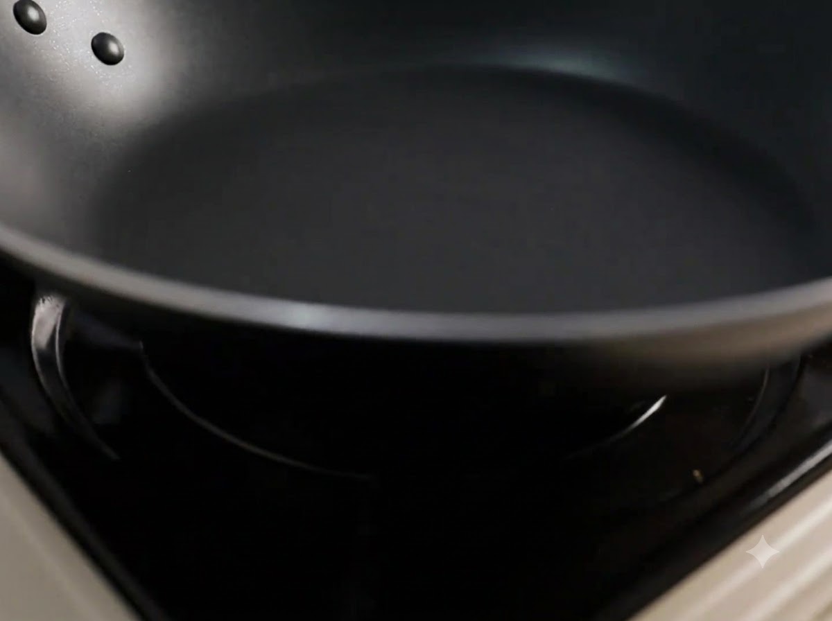 Olio da cucina versato in una padella nera riscaldata.