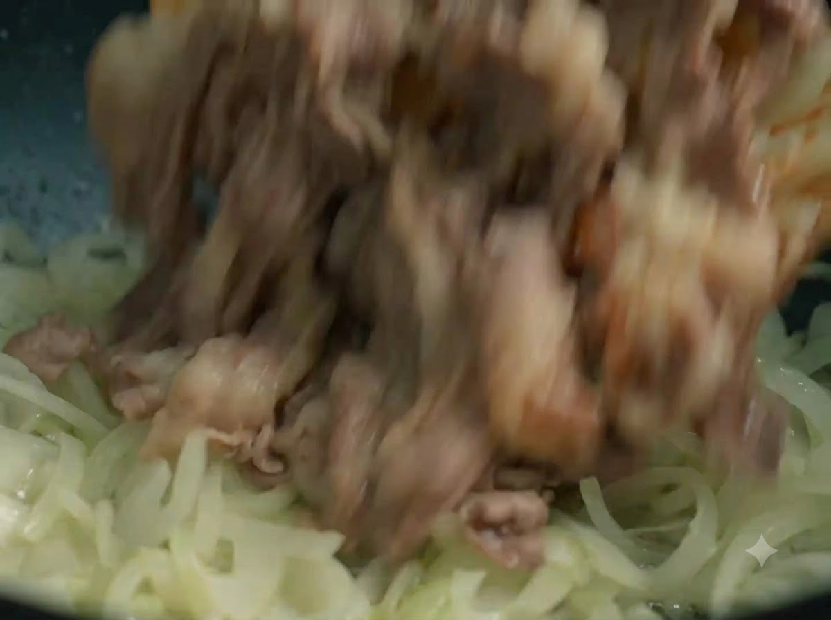 Fette di manzo cotte aggiunte nuovamente nel wok con le cipolle saltate.